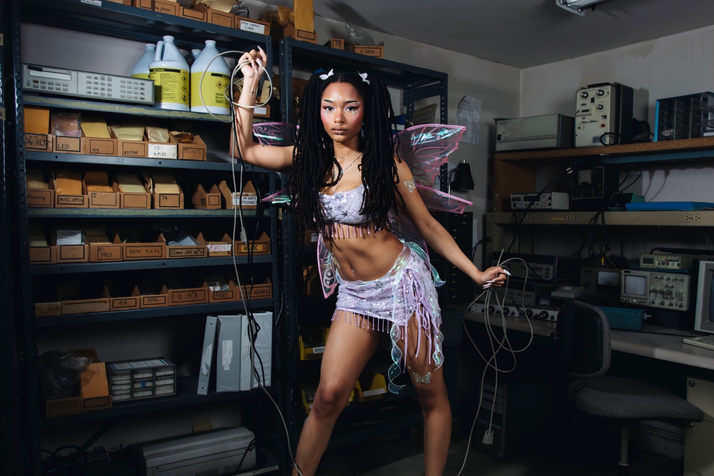KYIEMA holding a cable in a retro electronics lab